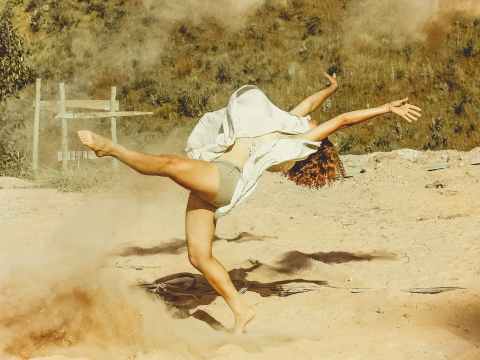 woman wearing white dress dancing on brown sand